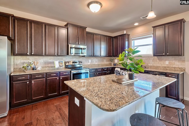 kitchen featuring a kitchen island, stainless steel appliances, a breakfast bar, and hanging light fixtures