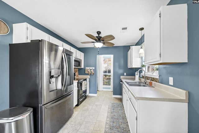 kitchen featuring appliances with stainless steel finishes, hanging light fixtures, ceiling fan, white cabinets, and sink