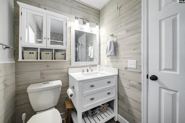 bathroom featuring toilet, vanity, and wood walls