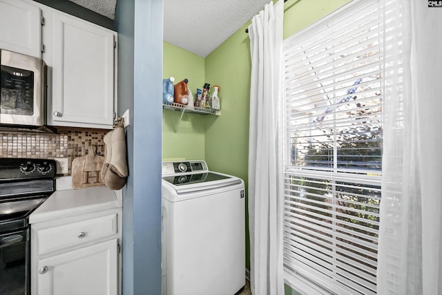 laundry area featuring washer / clothes dryer, a textured ceiling, and a healthy amount of sunlight