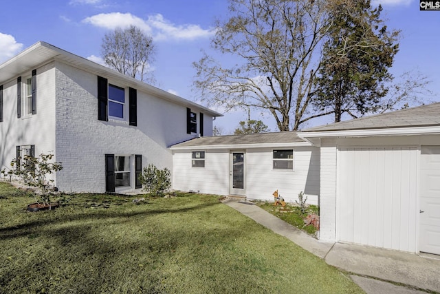 rear view of property featuring a lawn and a garage