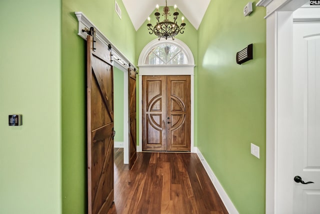 doorway to outside with dark hardwood / wood-style flooring, a chandelier, a barn door, and lofted ceiling