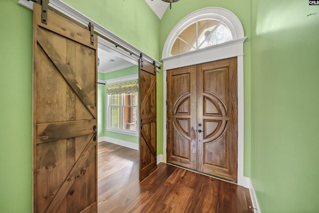 entrance foyer with dark hardwood / wood-style flooring, vaulted ceiling, and a barn door