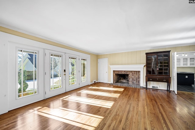 unfurnished living room with french doors, a fireplace, and hardwood / wood-style flooring