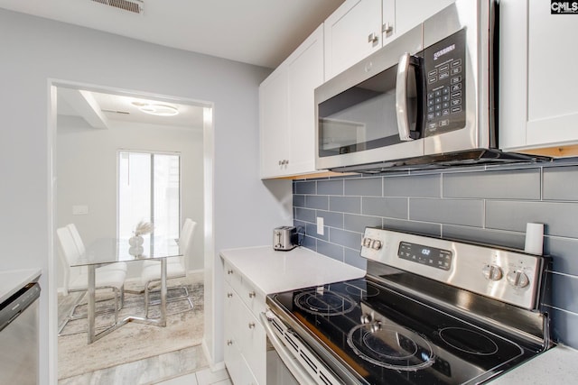 kitchen featuring stainless steel appliances, white cabinetry, and tasteful backsplash