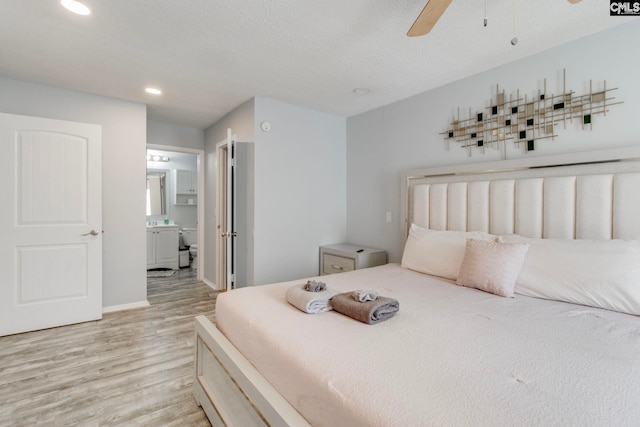 bedroom with ceiling fan, light wood-type flooring, ensuite bathroom, and a textured ceiling