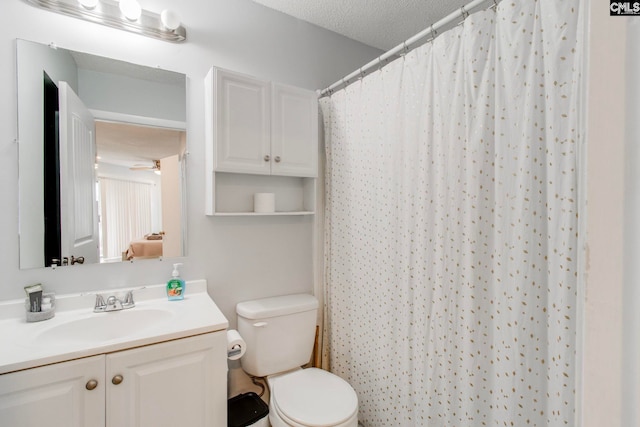 bathroom with curtained shower, a textured ceiling, ceiling fan, toilet, and vanity