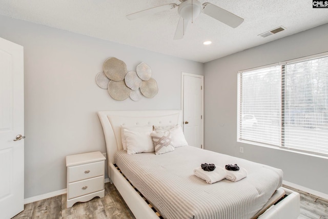 bedroom featuring ceiling fan, hardwood / wood-style floors, and multiple windows