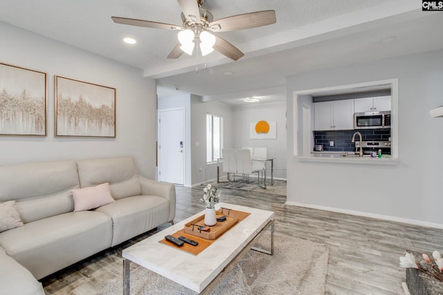 living room featuring sink, ceiling fan, and hardwood / wood-style flooring