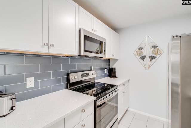 kitchen featuring white cabinets, light tile patterned flooring, decorative backsplash, light stone countertops, and appliances with stainless steel finishes