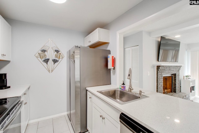 kitchen with sink, stainless steel appliances, white cabinetry, a fireplace, and light tile patterned floors