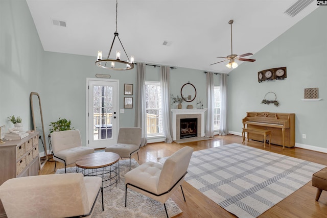 living room featuring light hardwood / wood-style flooring, lofted ceiling, and ceiling fan with notable chandelier