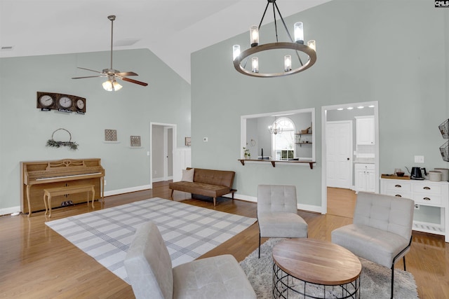 living room featuring light hardwood / wood-style flooring, high vaulted ceiling, and ceiling fan with notable chandelier