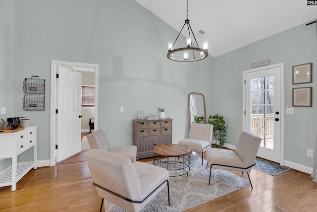 living area featuring high vaulted ceiling, a chandelier, and light hardwood / wood-style floors