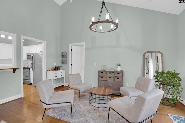 living room featuring a notable chandelier, light wood-type flooring, and high vaulted ceiling