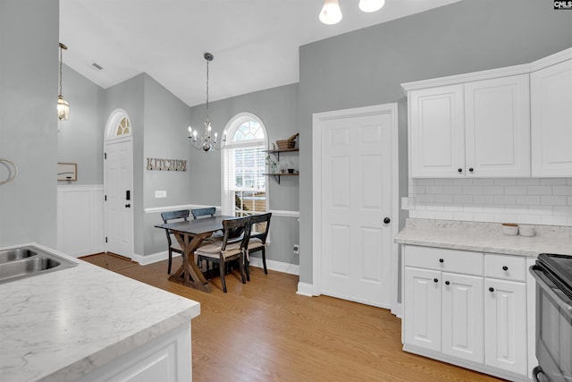 kitchen with lofted ceiling, white cabinetry, and tasteful backsplash