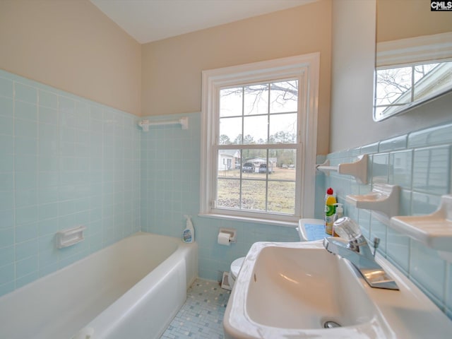 bathroom with sink, tile walls, toilet, tile patterned floors, and a tub to relax in