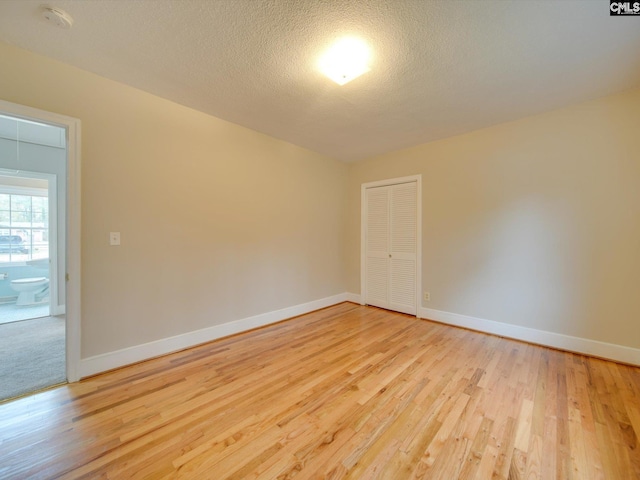 spare room with a textured ceiling and light wood-type flooring