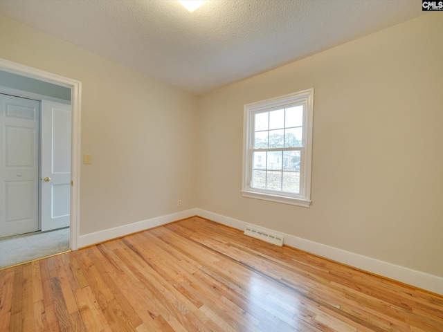 spare room featuring light hardwood / wood-style floors and a textured ceiling