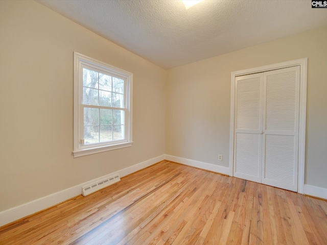 unfurnished bedroom with a closet, light wood-type flooring, and a textured ceiling