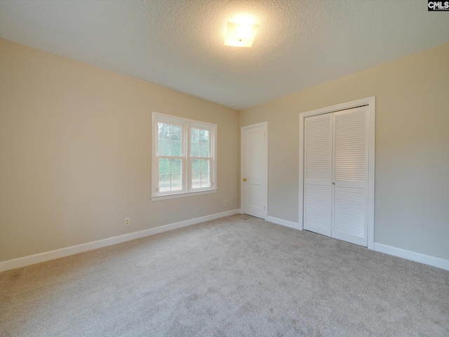 unfurnished bedroom with a textured ceiling, a closet, and light carpet