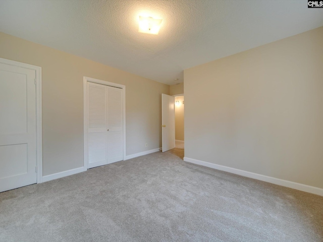 unfurnished bedroom featuring a textured ceiling, a closet, and light carpet