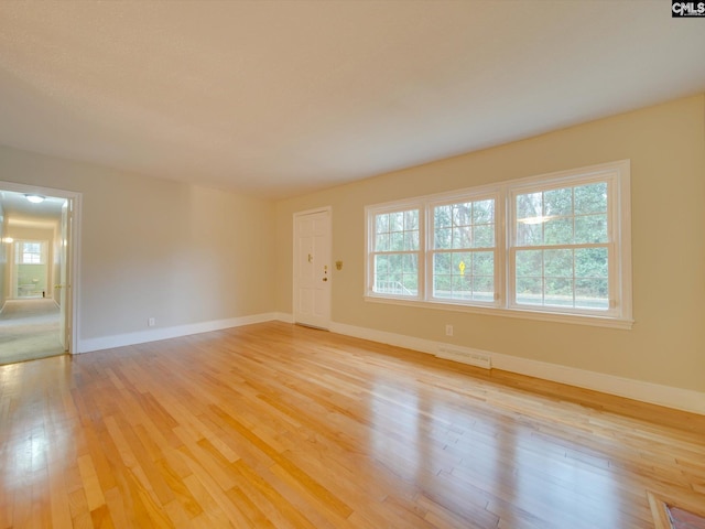 spare room featuring a wealth of natural light and light hardwood / wood-style floors