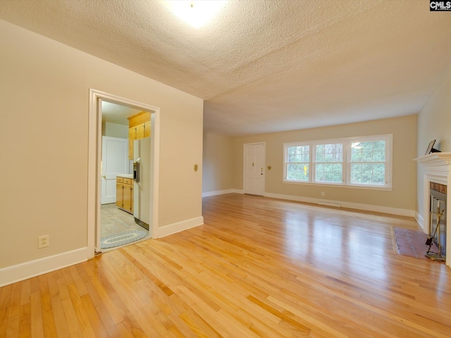 unfurnished living room with a textured ceiling and light wood-type flooring