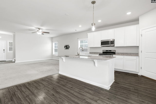 kitchen with decorative light fixtures, white cabinets, an island with sink, and appliances with stainless steel finishes