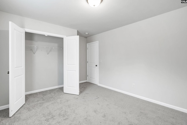 unfurnished bedroom featuring light colored carpet and a closet