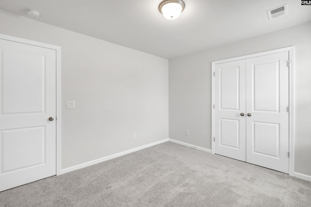 unfurnished bedroom with light colored carpet and a closet