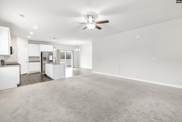 kitchen featuring decorative light fixtures, white cabinetry, ceiling fan with notable chandelier, stainless steel fridge with ice dispenser, and a center island with sink