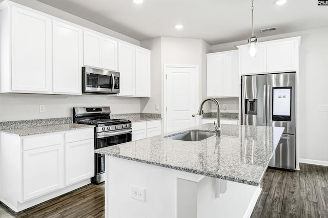 kitchen with stainless steel appliances, sink, white cabinetry, an island with sink, and dark hardwood / wood-style floors