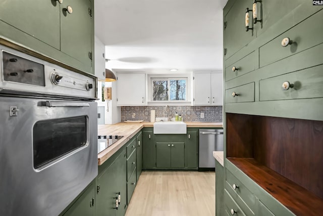 kitchen with appliances with stainless steel finishes, white cabinetry, sink, and green cabinets