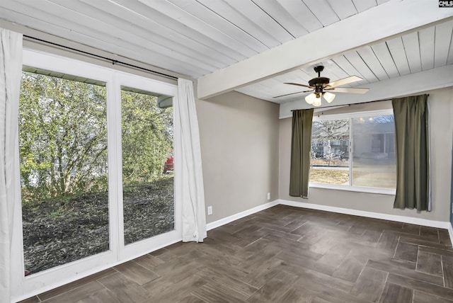 empty room featuring dark parquet flooring, ceiling fan, and beam ceiling