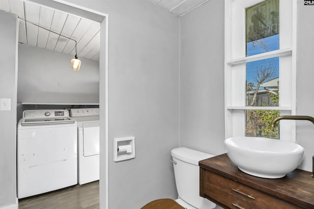 bathroom featuring toilet, washer and dryer, wood-type flooring, and sink