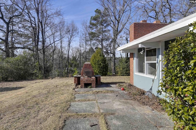 view of yard featuring a patio area and an outdoor brick fireplace