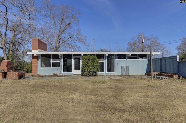 exterior space featuring a brick fireplace, a sunroom, and a yard