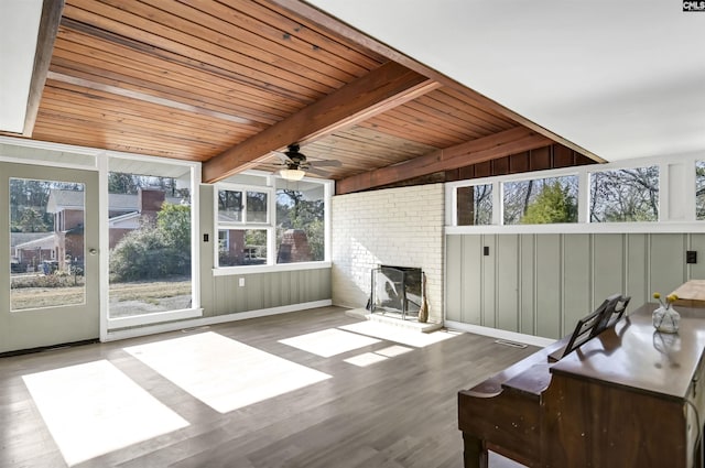 unfurnished sunroom featuring ceiling fan, wooden ceiling, beamed ceiling, and a fireplace