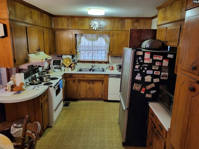 kitchen with white appliances, wood walls, ornamental molding, a textured ceiling, and sink