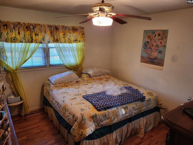 bedroom featuring ceiling fan, dark hardwood / wood-style flooring, and a textured ceiling