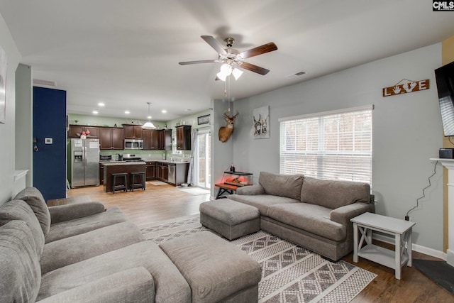 living room with ceiling fan and light wood-type flooring