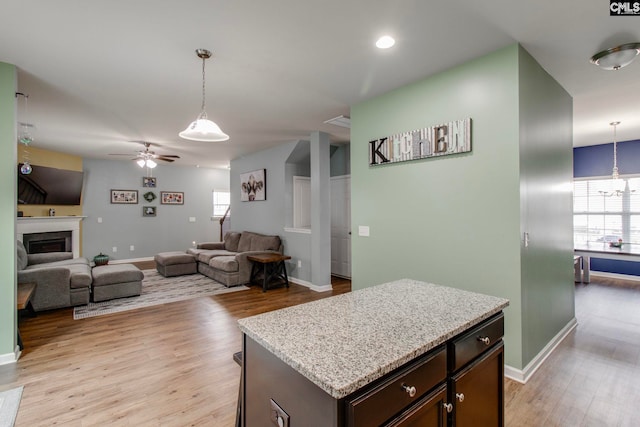 kitchen featuring ceiling fan, light hardwood / wood-style floors, a center island, and decorative light fixtures