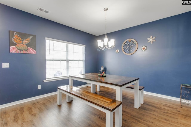 dining space featuring hardwood / wood-style flooring and an inviting chandelier