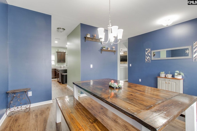 dining space with light hardwood / wood-style floors and a chandelier