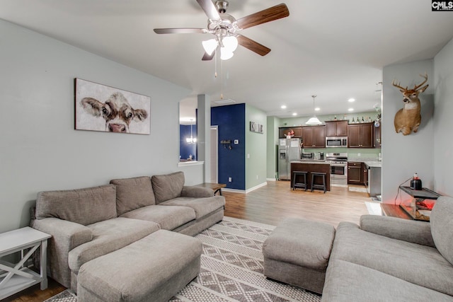 living room with ceiling fan and light hardwood / wood-style flooring