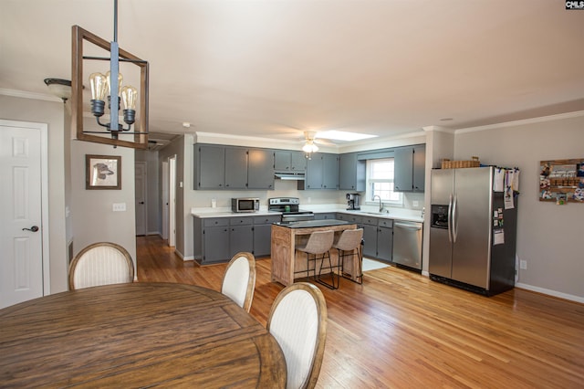 kitchen featuring a kitchen island, appliances with stainless steel finishes, gray cabinets, and ceiling fan with notable chandelier