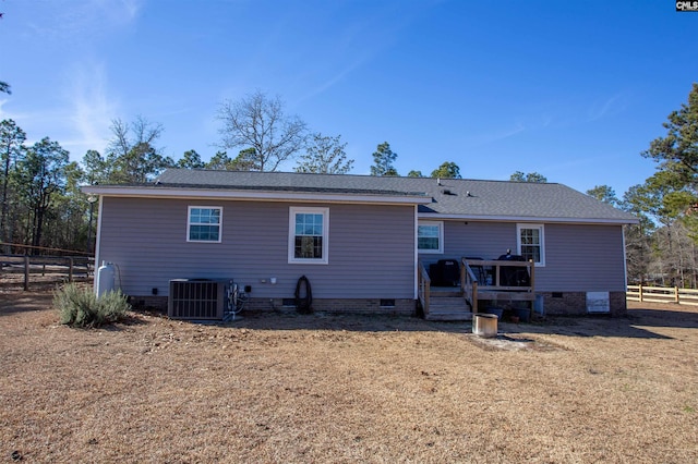 rear view of house with central air condition unit and a lawn