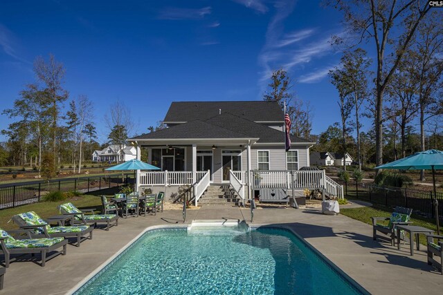 rear view of property featuring a pool side deck, a patio area, and a sunroom