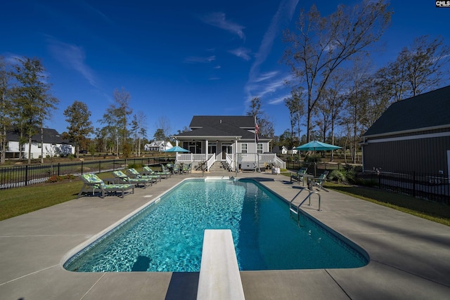 view of pool featuring an outbuilding, a diving board, and a patio area